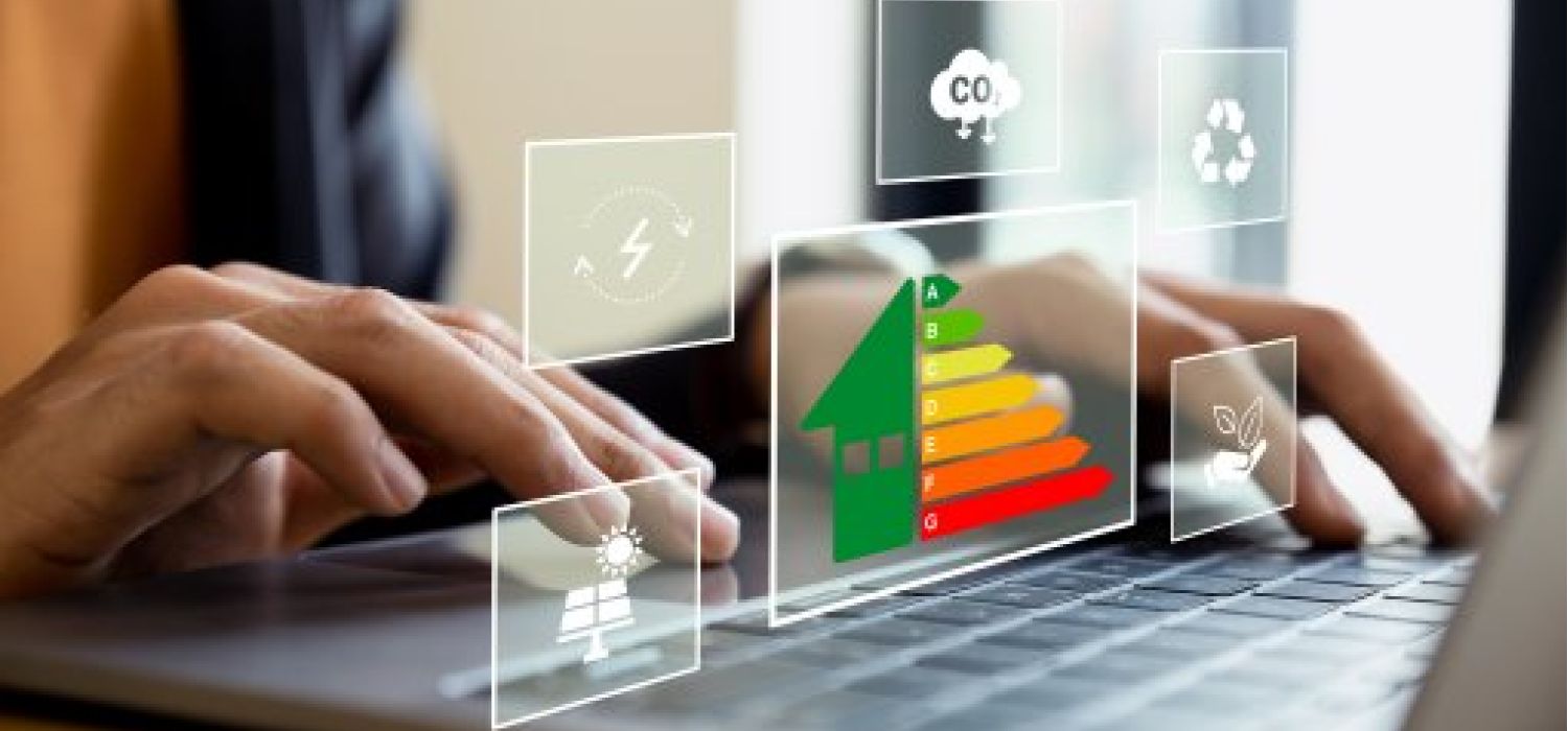 Mani su laptop con ologrammi digitali di scala energetica, icone di sostenibilità, pannelli solari e riduzione CO2 in sovrimpressione