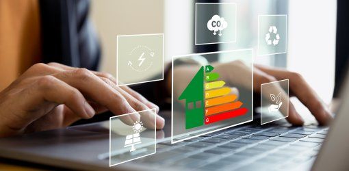 Mani su laptop con ologrammi digitali di scala energetica, icone di sostenibilità, pannelli solari e riduzione CO2 in sovrimpressione