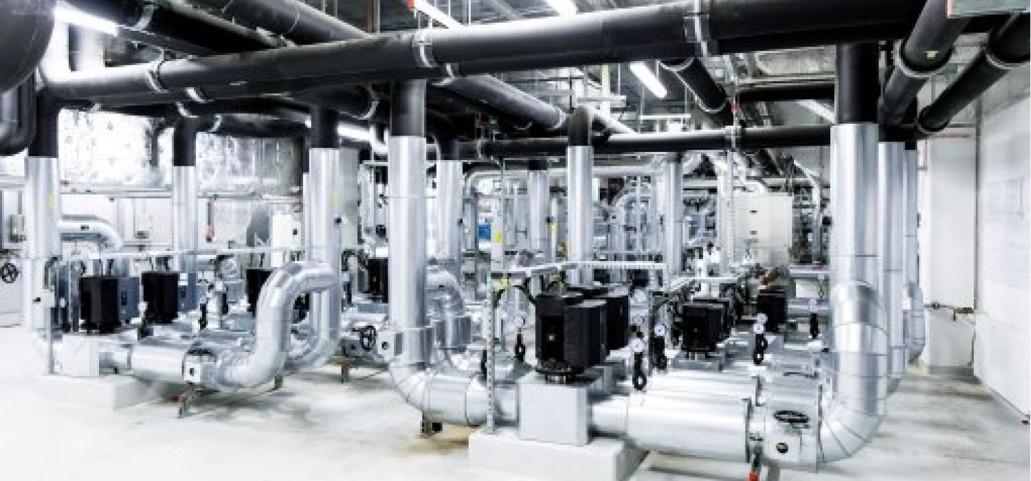 Centrale tecnologica industriale con rete di tubazioni in acciaio inox, pompe e impianti meccanici per la gestione di fluidi o climatizzazione